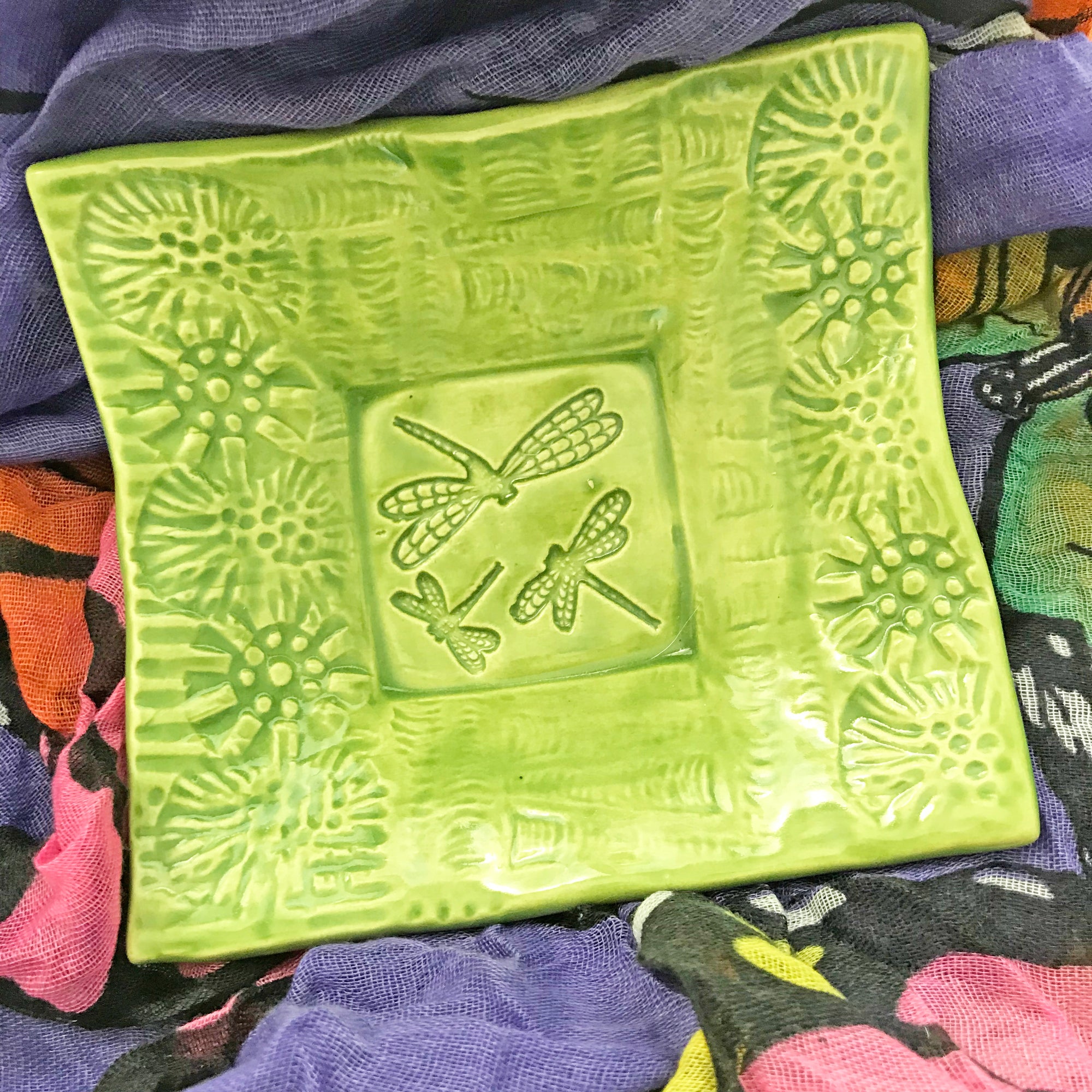 Handmade pottery dish with dragonfly design highlighted by the bright lime glaze.
