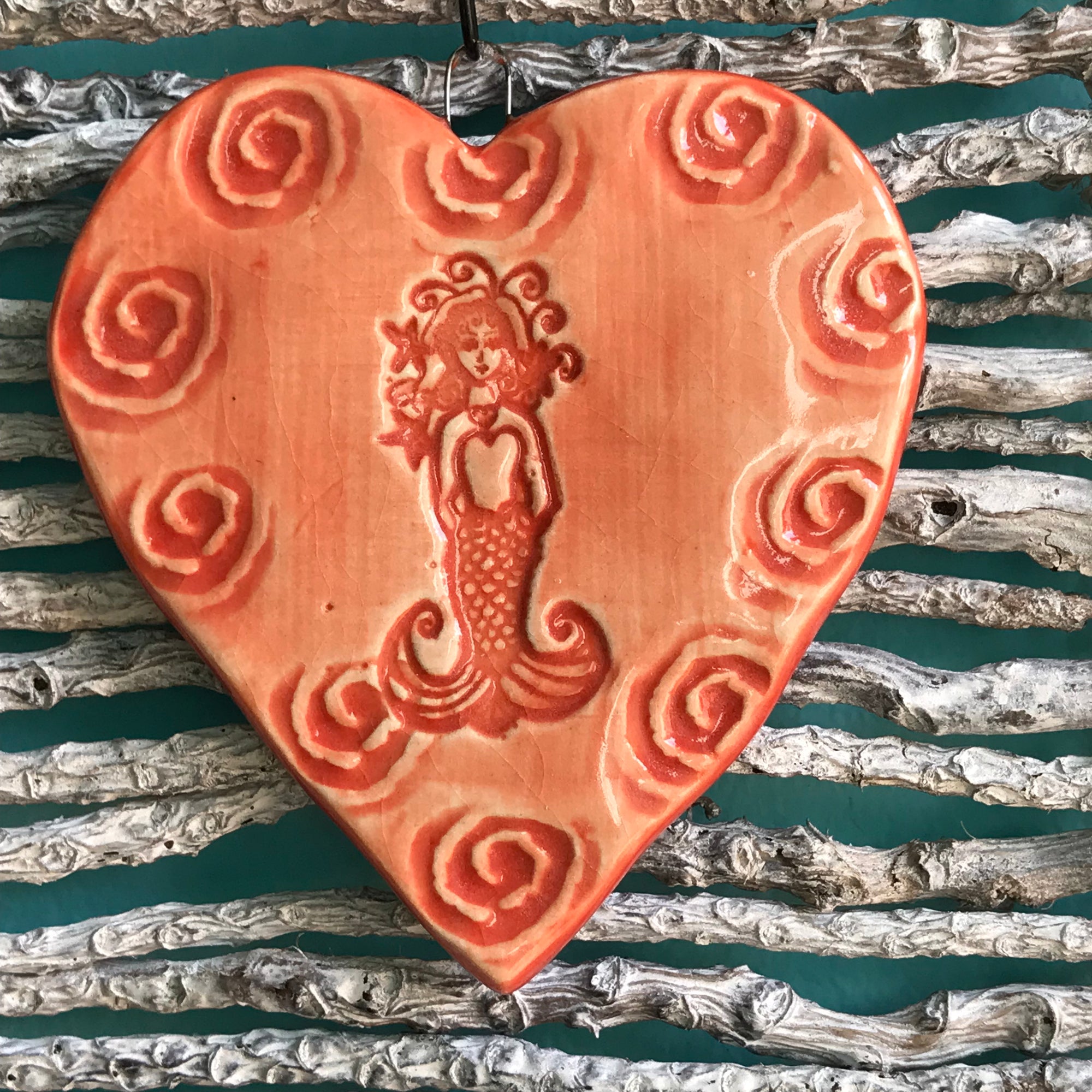 A mermaid ornament glazed in brilliant coral glaze.  Handmade and each has its own character.