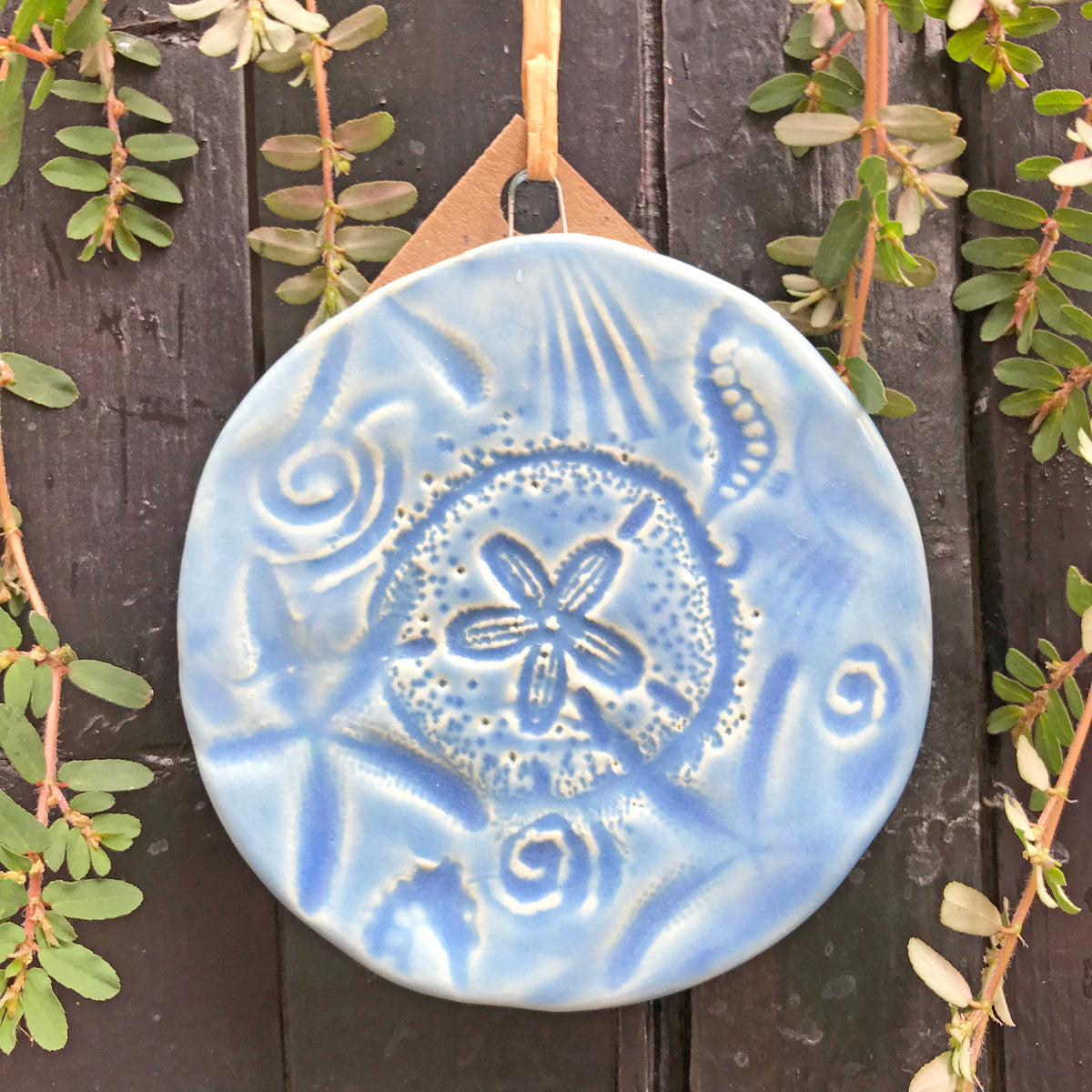 Sand Dollar Ornament crafted of earthenware clay and glazed a beautiful water-toned blue by the potters of Oerth Studio. 