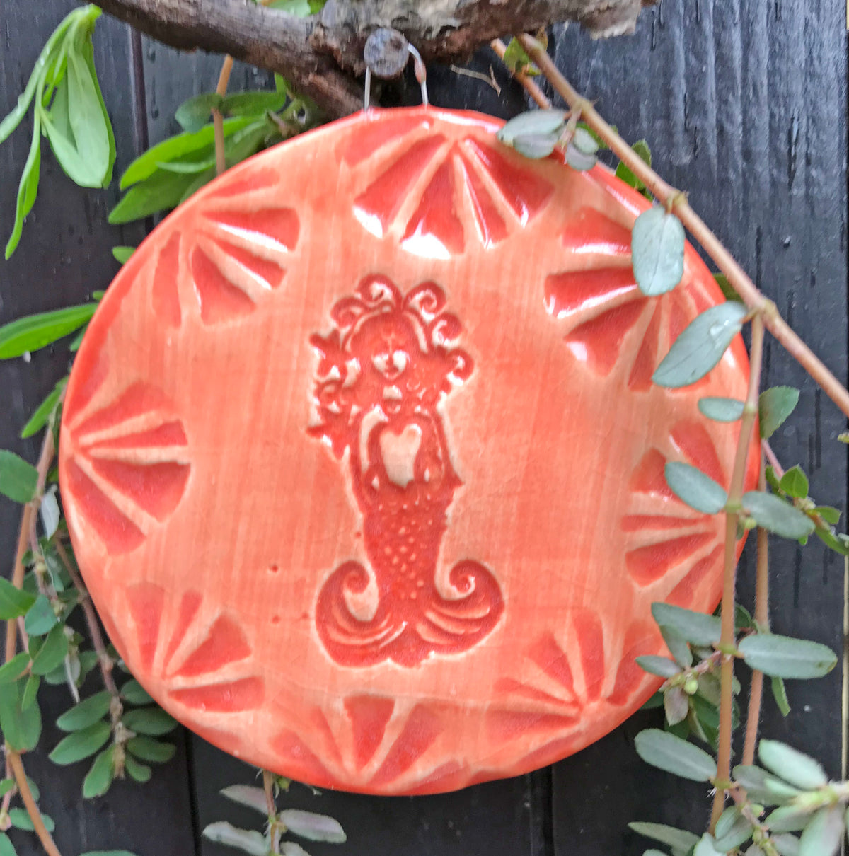 Mermaid Ornament created by the potters of Oerth Studio has a hand drawn mermaid glazed in bright coral orange. al coral.  So pretty against the green of a Christmas Tree. 