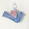 Handmade ornament shaped in folk art bird style, glazed with cobalt blue and heart wings. 
