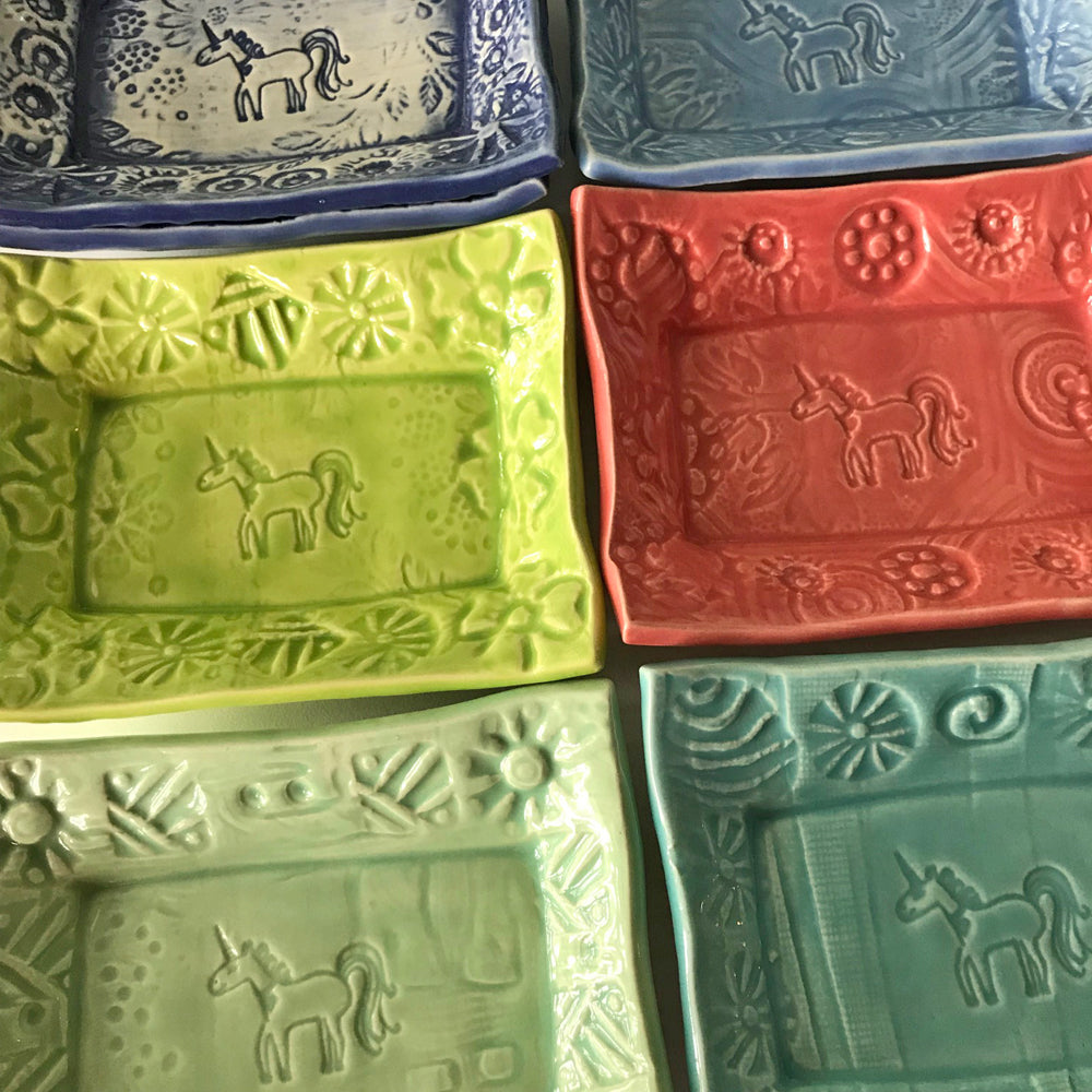 Soap Dish with Unicorn Design by Lorraine Oerth.  Shown in 6 of the best selling colors.  Greens, coral and blues.  Each is handmade and unique. 
